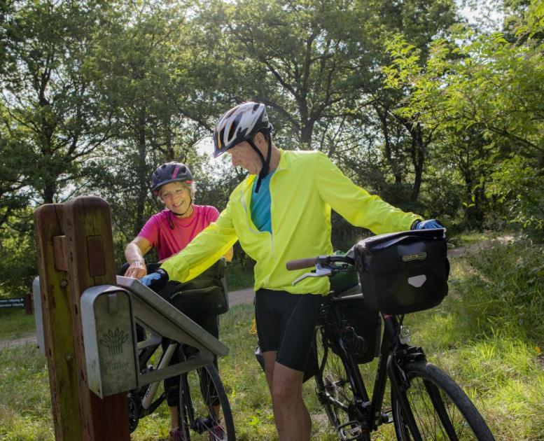 Ældre par på cykeltur kigger på skilt ved Gudenåens udspring