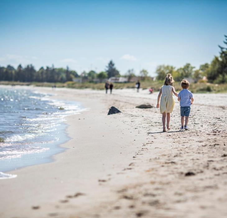 Børn går på stranden ved Saksild
